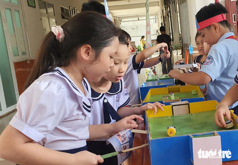 Dự ngày hội STEM, học sinh tiểu học ngạc nhiên Nhóm nữ sinh Trường tiểu học Lê Thị Hồng Gấm tỏ ra rất ngạc nhiên khi khám phá nguyên lý của trò chơi bóng đá nam châm - Ảnh: HOÀNG HƯƠNG
