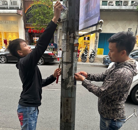 Đang dán quảng cáo hút hầm cầu lên cột đèn thì gặp công an- Ảnh 1. Hai thanh niên dán quảng cáo hút hầm cầu lên cột đèn bị buộc tẩy xóa, trả lại hiện trạng ban đầu - Ảnh: Công an cung cấp