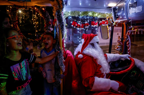 Ông già Noel cưỡi xe máy, lên rừng xuống bể phát quà Giáng sinh- Ảnh 5. Ông Edilson Santos hóa trang thành ông già Noel và lái chiếc xe buýt được trang trí theo chủ đề Giáng sinh tại thành phố Jardim Alzira Franco, ở bang Santo Andre (Brazil) vào ngày 19-12 - Ảnh: REUTERS