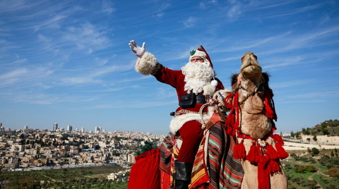 Ông già Noel cưỡi xe máy, lên rừng xuống bể phát quà Giáng sinh- Ảnh 11. Ông Issa Kassissieh mặc trang phục ông già Noel, cưỡi lạc đà đến thăm khu rừng ô liu ở Jerusalem (Israel) vào ngày 4-12 - Ảnh: REUTERS
