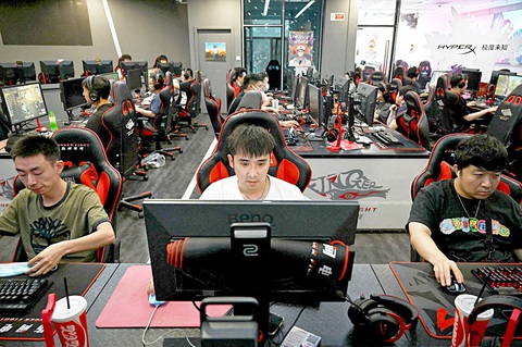 Trung Quốc siết game online, ngăn game thủ đốt tiền- Ảnh 1. Người chơi game dán mắt vào màn hình máy tính tại một quán cà phê Internet ở Bắc Kinh, Trung Quốc vào tháng 9-2021 - Ảnh: AFP
