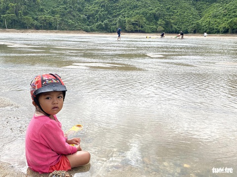 Hậu giấc mơ đào vàng, máu và nước mắt - Kỳ 2: Phận nghèo ở thủ phủ vàng- Ảnh 5. Em bé ngồi trên bờ chờ mẹ mót vàng kiếm miếng ăn trên sông Nước Mỹ - Ảnh: LÊ TRUNG