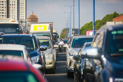 Người dân về quê chơi Tết dương lịch, các cửa ngõ TP.HCM xe nối dài rồng rắn- Ảnh 2. Xe máy luồn lách qua từng kẽ hở của dòng xe ô tô để vượt qua đoạn kẹt ở cửa ngõ phía đông TP.HCM - Ảnh: CHÂU TUẤN
