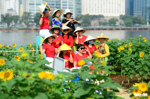 Bất chấp nắng nóng, người dân TP.HCM về trung tâm chơi Tết dương lịch- Ảnh 3. Một nhóm phụ nữ quay clip tập thể dục nhịp điệu sau đó lưu lại kỷ niệm cùng nhau cạnh cánh đồng hoa hướng dương - Ảnh: QUANG ĐỊNH