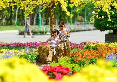 Bất chấp nắng nóng, người dân TP.HCM về trung tâm chơi Tết dương lịch- Ảnh 5. Hai em nhỏ đi chơi tại công viên Lê Văn Tám, quận 1, TP.HCM sáng 31-12 - Ảnh: QUANG ĐỊNH