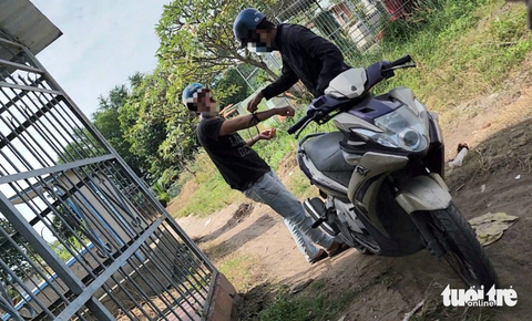 Nghĩa trang Bình Hưng Hòa giờ thành điểm hút chích ma túy giữa ban ngày- Ảnh 3. Sáng 4-12, hai người đàn ông đi xe máy dừng xe tại lối đi cạnh khu mộ trong nghĩa trang. Trong đó, một người lấy kim tiêm ra để chích - Ảnh: MINH HÒA
