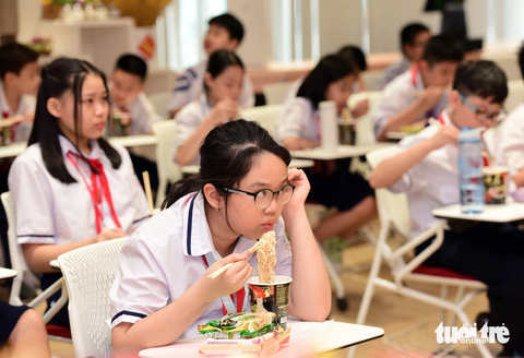 Học sinh thích thú tham gia hoạt động nhóm khi đi thực tế- Ảnh 3. Các em thích thú thưởng thức mì ly khi đến tham quan nhà máy - Ảnh: DUYÊN PHAN