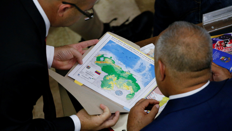 Venezuela muốn lấy phần đất Guyana giàu dầu mỏ, Nam Mỹ ngửi thấy mùi chiến tranh- Ảnh 1. Các thành viên Quốc hội Venezuela xem bản đồ các khu vực tranh chấp với Guyana ngày 6-12, khi căng thẳng hai nước láng giềng gia tăng vì nguồn lợi từ một mỏ dầu mới - Ảnh: REUTERS