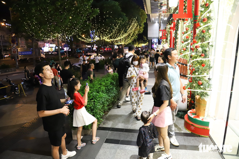 Trung tâm TP.HCM lên đèn rực rỡ, người dân 'lên đồ' xuống phố đón Giáng sinh sớm- Ảnh 8. Hàng cây thông trang trí dọc trung tâm thương mại trên đường Lê Lợi (quận 1) thu hút đông đảo người dân đến tham quan tối 9-12