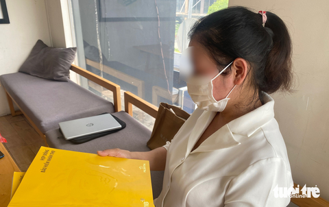 'Ép' người dân mua bảo hiểm: Không mua bảo hiểm, chấm dứt khoản vay - Ảnh 8. Chị Giang cầm trên tay hai hợp đồng bảo hiểm nhân thọ (VIB hợp tác với Prudential), sau khi vay vốn tại ngân hàng Ảnh: BÔNG MAI