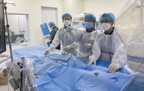 Gầy dựng tinh thần y khoa dấn thân - Ảnh 4. Bác sĩ Đỗ Nguyên Tín (giữa) đang thực hiện ca can thiệp cho một bệnh nhân tim bẩm sinh mà ông phát hiện từ đợt khám từ thiện hồi tháng 12-2022. Ca can thiệp này diễn ra tại Bệnh viện Đa khoa tỉnh Khánh Hòa vào ngày 24-2. Hôm nay (25-2) ông lại cùng cộng sự khám sàng lọc bệnh tim miễn phí cho trẻ em và bà con nghèo huyện Sông Hinh, tỉnh Phú Yên - Ảnh: N.T.