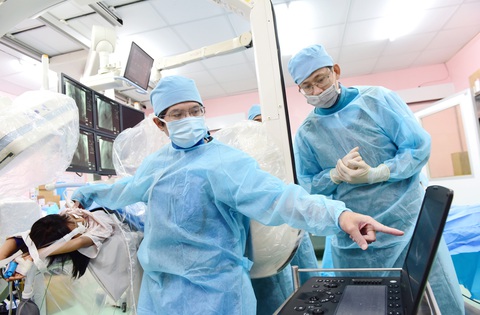 Gầy dựng tinh thần y khoa dấn thân - Ảnh 2. Bác sĩ Đỗ Nguyên Tín (trái) đang khám cho một bệnh nhi và truyền nghề cho đồng nghiệp trẻ - Ảnh: DUYÊN PHAN