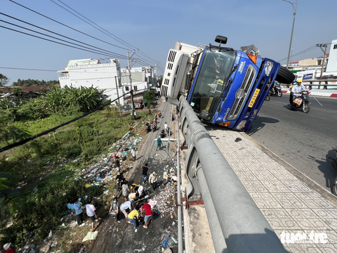 Người dân cùng giúp tài xế xe tải lật trên cầu Kênh Xáng gom cá - Ảnh 1. Người dân cùng giúp tài xế xe tải lật trên cầu Kênh Xáng gom cá - Ảnh 1.