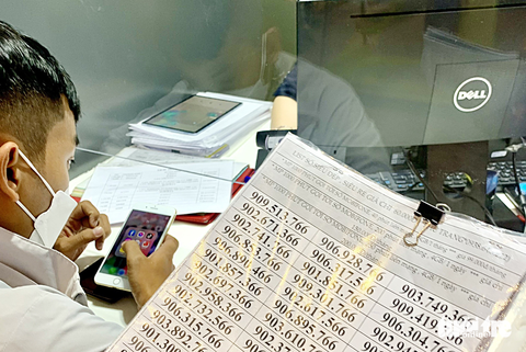 Chuẩn hóa thông tin chủ thuê bao di động: Làm sớm để bớt cuộc gọi lừa đảo - Ảnh 1. Khách tìm số để làm SIM điện thoại di động tại cửa hàng MobiFone ở TP.HCM chiều 13-3 - Ảnh: T.T.D.