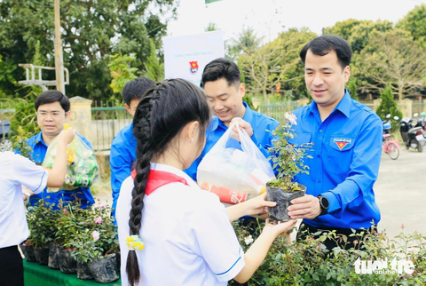 Bạn trẻ Nghệ An rộn ràng ra quân 'Ngày chủ nhật xanh' toàn quốc - Ảnh 1. Anh Ngô Văn Cương - bí thư Trung ương Đoàn - trao cây xanh cho các bạn học sinh - Ảnh: DOÃN HÒA