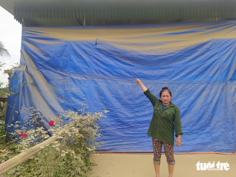 Khổ sở sống bên con đường đang thi công đầy bụi - Ảnh 3. Bà Phan Thị Nga bên trấm bạt giăng trước cửa nhà đầy bụi bám vào - Ảnh: LÊ MINH