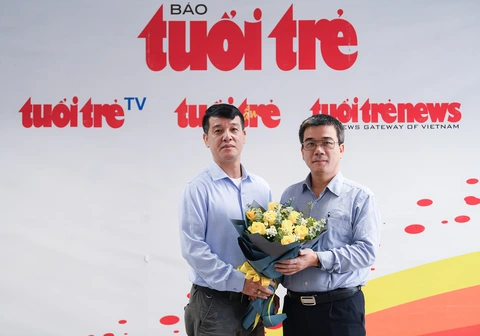 Đang giao lưu trực tuyến: Lưu ý gì khi ký hợp đồng mua bảo hiểm nhân thọ? - Ảnh 3. Đại diện Báo Tuổi Trẻ Văn phòng Hà Nội (trái) tặng hoa cho ông Ngô Trung Dũng - phó tổng thư ký Hiệp hội Bảo hiểm Việt Nam - Ảnh: NAM TRẦN