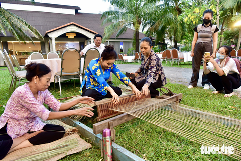 Xem dệt chiếu cói , nướng bánh phồng, làm bánh phục linh... tại lễ hội văn hóa ẩm thực - Ảnh 3. Khách (ở giữa) được hướng dẫn cách dệt chiếu cói tại khu làng nghề - Ảnh: T.T.D.