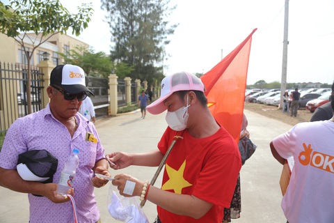 Người Khmer gốc Việt phát khăn, cờ cho cổ động viên các nước - Ảnh 3. Anh Điệp tặng các miếng dán cho cổ động viên Thái Lan - Ảnh: HUY ĐĂNG