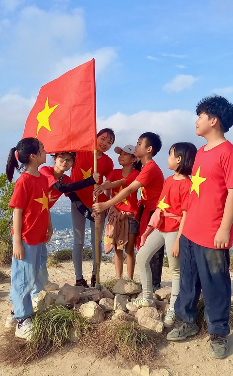 Các em học sinh và phụ huynh cắm cờ trên đỉnh Cô Tiên - Ảnh: THỤC NGHI Các em học sinh và phụ huynh cắm cờ trên đỉnh Cô Tiên - Ảnh: THỤC NGHI