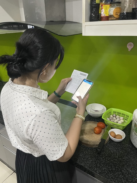 Thu học phí không tiền mặt: nỗi lo nhiều app - Ảnh 1. Chị Trần Kim Phụng vừa làm bếp vừa thanh toán học phí cho con học tại Trường THPT Bình Tân