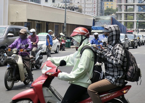 Nam Bộ nắng nóng 39 độ C, người dân tìm đủ cách trú nắng - Ảnh 2. Hai bạn trẻ mặc áo chống nóng khi đi trên đường ở trung tâm TP.HCM trưa 5-5 - Ảnh: T.T.D.