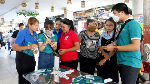 Khởi động hè tình nguyện ở tuổi 30 - Ảnh 1. Các bạn trẻ tư vấn cho tiểu thương, bà con sử dụng thanh toán không tiền mặt tại chợ Nguyễn Tri Phương sau lễ ra quân hè tình nguyện quận 10 (TP.HCM) ngày 10-6 - Ảnh: K.ANH