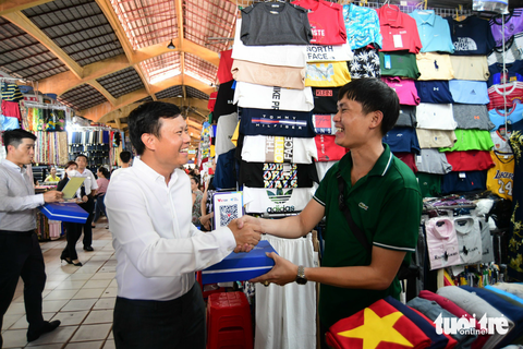 Tiểu thương chợ Bến Thành nô nức nhận mã thanh toán không tiền mặt - Ảnh 4. Ông Nguyễn Đức Huỳnh – Trưởng đại diện tại TP.HCM của Công ty cổ phần Thanh toán quốc gia Việt Nam NAPAS - trao mã QR thanh toán không tiền mặt cho tiểu thương - Ảnh: QUANG ĐỊNH