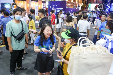 Khách đến lễ hội Không tiền mặt đông nghẹt, ngân hàng mở thêm giải thưởng trúng vàng và xe - Ảnh 9. Nhân viên của quầy Napas tư vấn cho khách cách thanh toán trực tuyến, tối 17-6 - Ảnh: PHƯƠNG QUYÊN