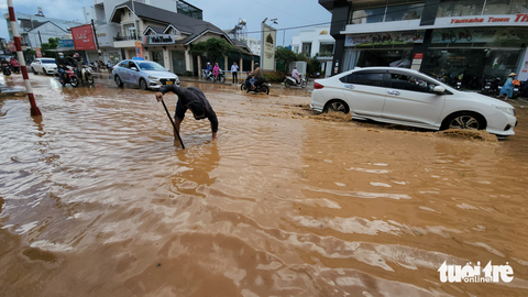 Đà Lạt mưa to, nhiều đoạn đường ngập nặng, dân vừa khóc vừa tát nước - Ảnh 2. Người dân thông các lỗ thoát nước trên đường Phan Đình Phùng đang bị ngập - Ảnh: M.V.