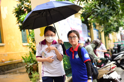 Tình nguyện viên hỗ trợ sinh viên ra xe ra về - Ảnh: DUYÊN PHAN Tình nguyện viên che dù đưa thí sinh ra về - Ảnh: DUYÊN PHAN