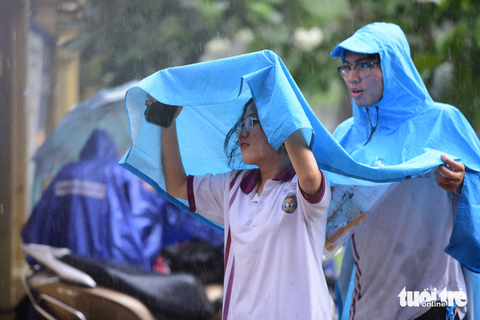 - Ảnh: DUYÊN PHAN Thí sinh che áo mưa ra về sau buổi làm thủ tục dự thi - Ảnh: DUYÊN PHAN