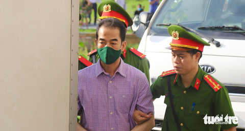 Hôm nay 11-7, xét xử cựu thứ trưởng Tô Anh Dũng cùng 53 người vụ 'chuyến bay giải cứu' - Ảnh 1. Ông Tô Anh Dũng - cựu thứ trưởng Bộ Ngoại giao được cảnh sát áp giải vào phòng xét xử - Ảnh: DANH TRỌNG