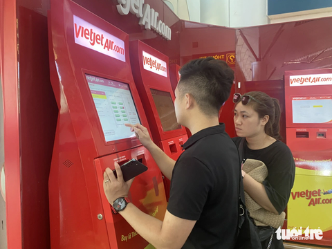 Sân bay Đà Nẵng đông kín người vì điều chỉnh lịch bay - Ảnh 3. Hành khách tranh thủ làm thủ tục online để bớt cảnh chen lấn - Ảnh: TRƯỜNG TRUNG