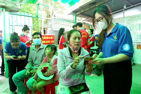 Cùng hành động vì xã hội số - Ảnh 1. Chiến sĩ tình nguyện hướng dẫn người dân thủ tục hành chính ở bộ phận một cửa tại UBND huyện Bình Chánh - Ảnh: K.ANH