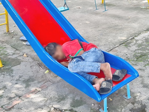 Mùa hè không có tiếng ve kêu - Kỳ 4: Nghỉ hè, lên thành phố kiếm tiền đi học - Ảnh 2. Bé Thạch Huy trên đường đi bán vé số đã dừng lại chơi trò chơi ngoài trời và lim dim ngủ luôn trên máng trượt - Ảnh: MẠNH DŨNG