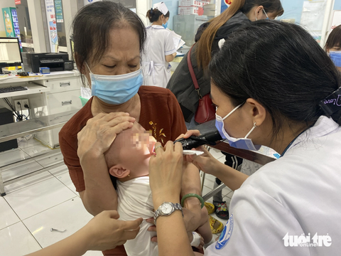 Tay chân miệng - Ảnh 2. Bác sĩ thăm khám vết loét trong miệng bệnh nhi mắc tay chân miệng đang điều trị tại khoa nhiễm - thần kinh Bệnh viện Nhi đồng 1 (TP.HCM) - Ảnh: X.MAI