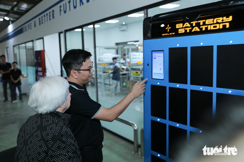 Bộ trưởng Tài chính Mỹ thử xe máy điện của startup Việt Nam - Ảnh 3. Bộ trưởng Yellen đi dạo tham quan dây chuyền sản xuất lắp ráp xe máy điện và đang quan sát hệ thống trạm ATM pin cho xe máy điện của Selex - Ảnh: DANH KHANG