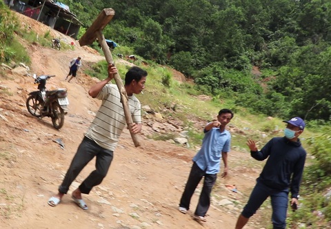 Xác minh vụ người dân khai thác vàng trái phép, nhóm phóng viên bị đòi đánh khi tác nghiệp - Ảnh 1. Người đàn ông ở bãi vàng dùng vật dụng bằng gỗ đuổi, đòi đánh phóng viên tác nghiệp, ghi nhận tình trạng khai thác vàng trái phép - Ảnh cắt từ clip của nhóm phóng viên