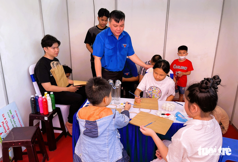 Quận 10 mở 14 điểm tiếp nhận túi ni lông, rác nhựa - Ảnh 3. Các em nhỏ tô màu lên túi giấy và nhận quà là các chai đựng nước sử dụng được nhiều lần