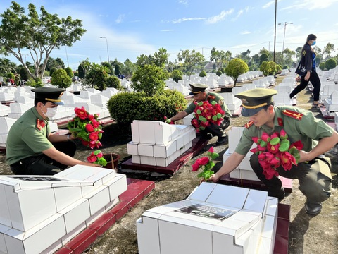 Tuổi trẻ Công an Kiên Giang: Lau chùi và thay hoa mới cho hơn 4.495 mộ phần liệt sĩ - Ảnh 1. Các đoàn viên thanh niên Công an tỉnh Kiên Giang cắm lên những đóa hoa để tri ân anh hùng liệt sĩ - Ảnh: TRƯƠNG QUỐC