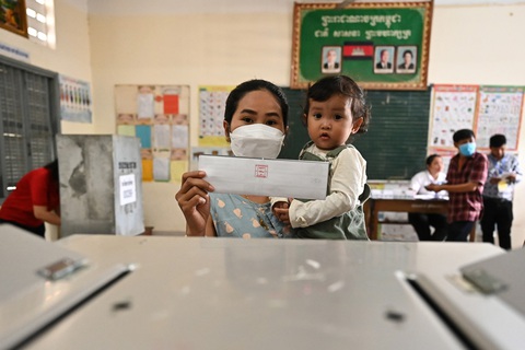Nữ cử tri bế con đi bầu tại điểm bỏ phiếu tại thủ đô Phnom Penh - Ảnh: AFP Nữ cử tri bế con đi bầu tại thủ đô Phnom Penh. Công tác bỏ phiếu sẽ kết thúc lúc 15h cùng ngày - Ảnh: AFP