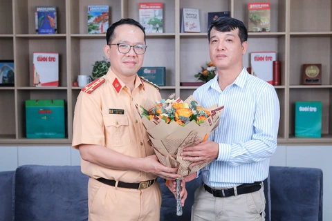 Những điều cần biết về đấu giá biển số ô tô và biển số định danh - Ảnh 1. Đại diện báo Tuổi Trẻ tặng hoa cho Đại tá Nguyễn Quang Nhật (trái) - Ảnh: DANH KHANG