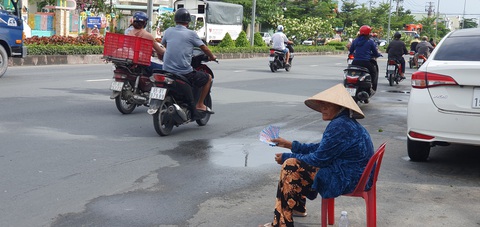 Tràn xuống đường bán vé số ở miền Tây - Ảnh 8. Chiều 25-7, một người phụ nữ lớn tuổi bắt ghế ngồi dưới lòng đường đường 3-2 (phường An Bình, quận Ninh Kiều, TP Cần Thơ) để bán vé số.