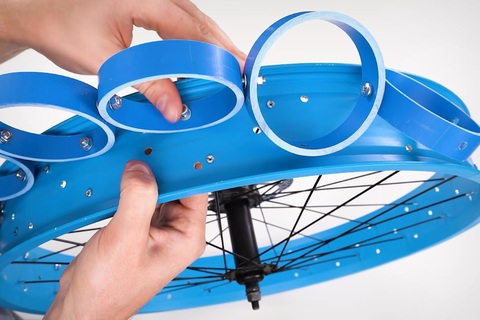 Tự chế lốp xe 'xịn' từ ống nhựa, không cần máy in 3D, không cần bơm, giá 'hạt rẻ' - Ảnh 5. Khi đã có được vài trăm vòng nhựa, anh khoan lỗ, gắn vào vành bánh xe bằng ốc vít. Mỗi bánh cần 66 vòng nhựa xếp thành 3 hàng, mỗi hàng 22 vòng, tổng cộng 132 vòng - Ảnh: The Q/YouTube