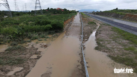 Ngập trên cao tốc Phan Thiết - Dầu Giây: 'Cống nằm vị trí thấp, không kịp thoát nước' - Ảnh 4. Nước ngập làm hư đường gom dân sinh cạnh tuyến cao tốc - Ảnh: ĐỨC TRONG