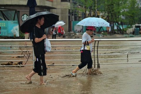 Mưa lớn 40 giờ liên tục biến đường phố Bắc Kinh thành sông, 2 người thiệt mạng - Ảnh 2. Người dân đi trên đường phố ngập nước tại quận Môn Đầu Câu, Bắc Kinh - Ảnh: AFP