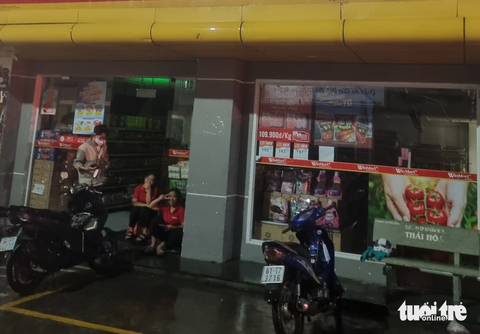 Mưa lớn gây sự cố lưới điện, nhiều khu dân cư tại Bình Dương bị cúp điện - Ảnh 4. Do không có máy phát, nhân viên một siêu thị phải tạm ngưng kinh doanh ra trước cửa siêu thị ngồi chờ - Ảnh: BÁ SƠN