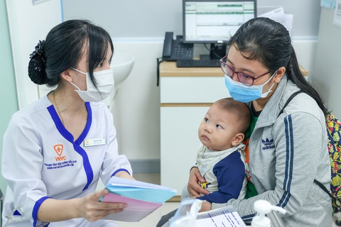 Theo chân hành trình cõng vắc xin lên núi - Ảnh 1. Một người mẹ đưa con đến trung tâm tiêm chủng để tiêm vắc xin