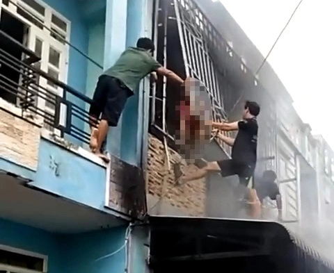 Người dân phá rào sắt cứu 3 người thoát khỏi căn nhà xảy ra cháy - Ảnh 1. Người dân phá rào sắt để ba người trong gia đình anh H. thoát ra ngoài - Ảnh cắt từ clip do người dân ghi lại